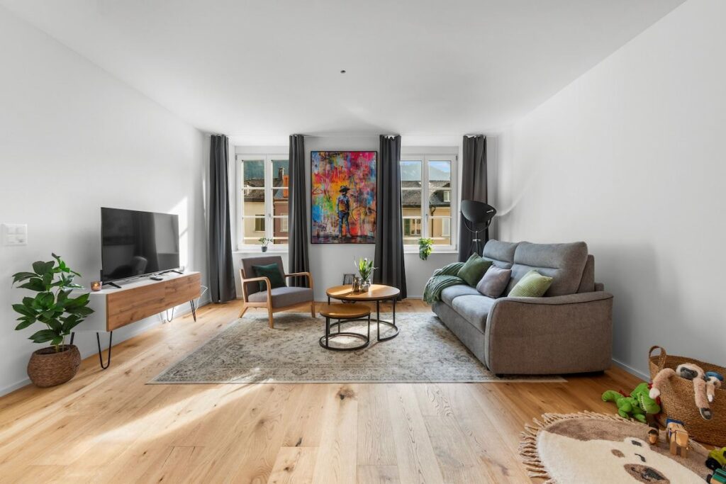 Wohnzimmer mit Bettsofa, Sessel und Smart-TV